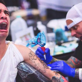 man in pain getting tattoo